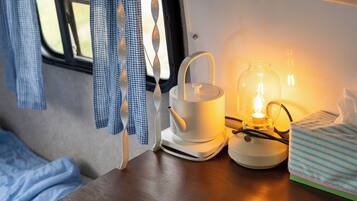 A cozy interior with a kettle, a glass jar with a light, and a striped towel on a table.