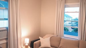 A cozy room with a beige sofa, a small table with a lamp, and a radiator. - Summer Home Close to Beach, Ocean, LIRR w/Balcony (Long Beach)