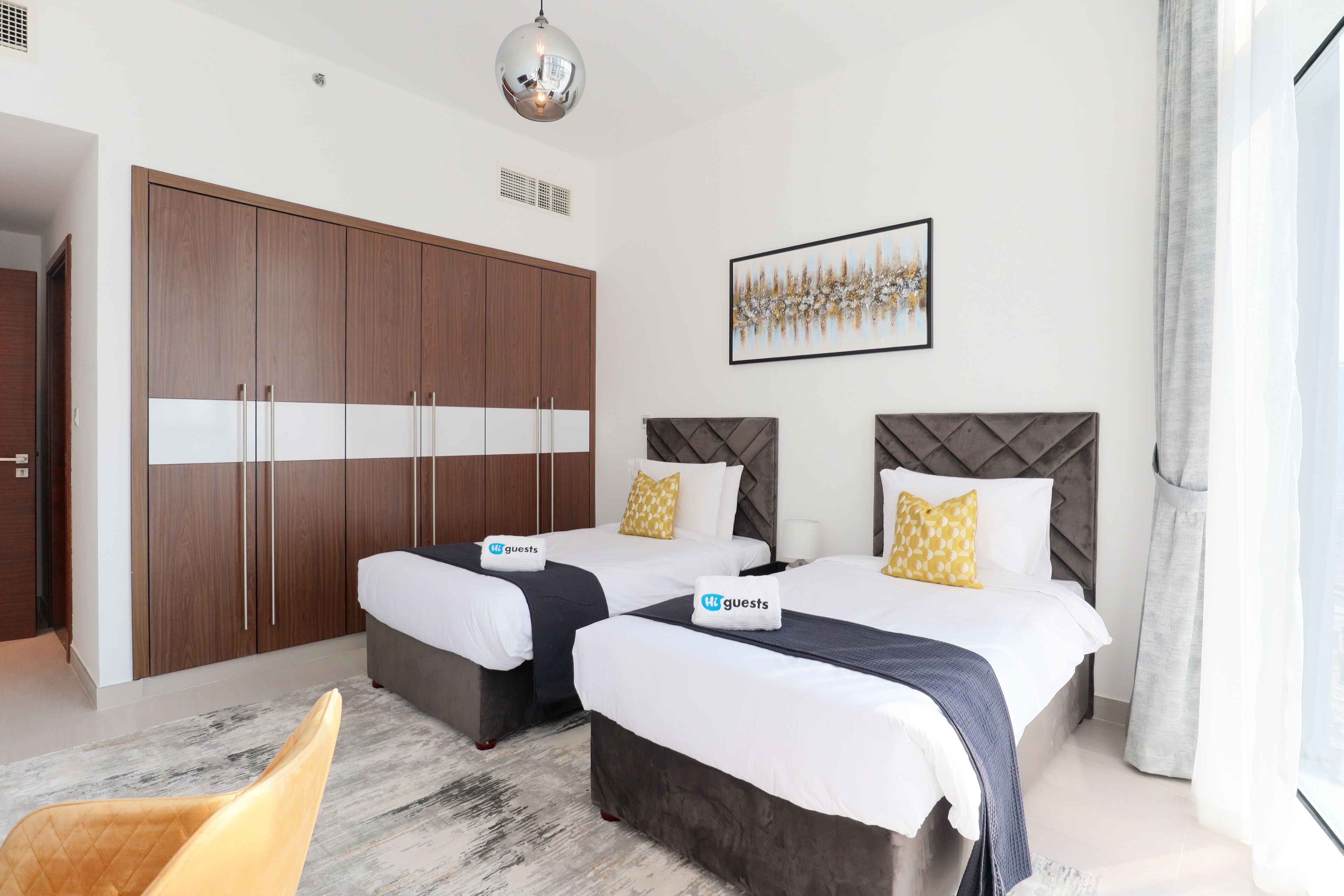 A hotel room with two beds, a wardrobe, a painting, and a view of the outdoors.