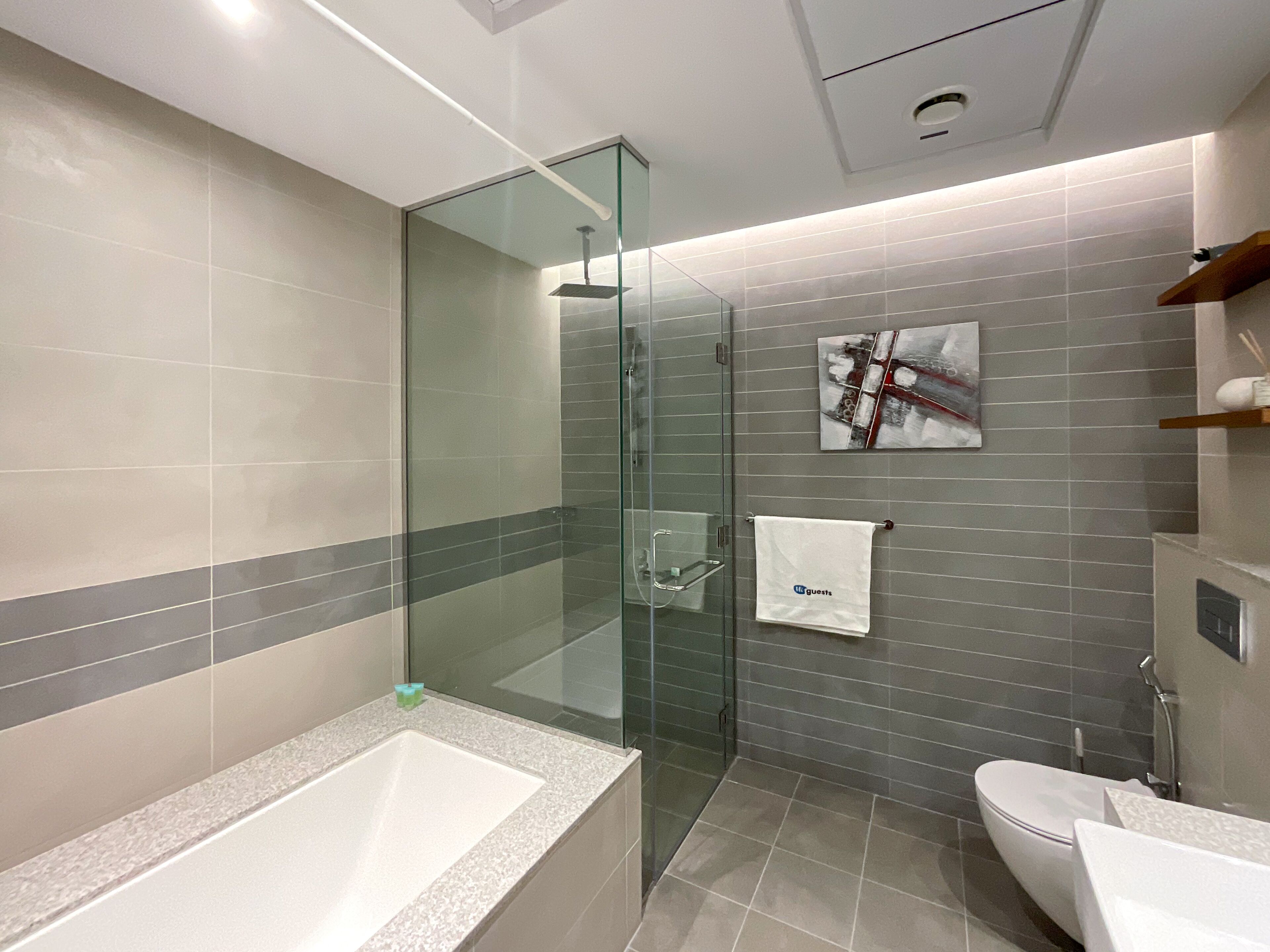 Et moderne badeværelse med en glasafskærmet brusekabine, et badekar og et toilet.