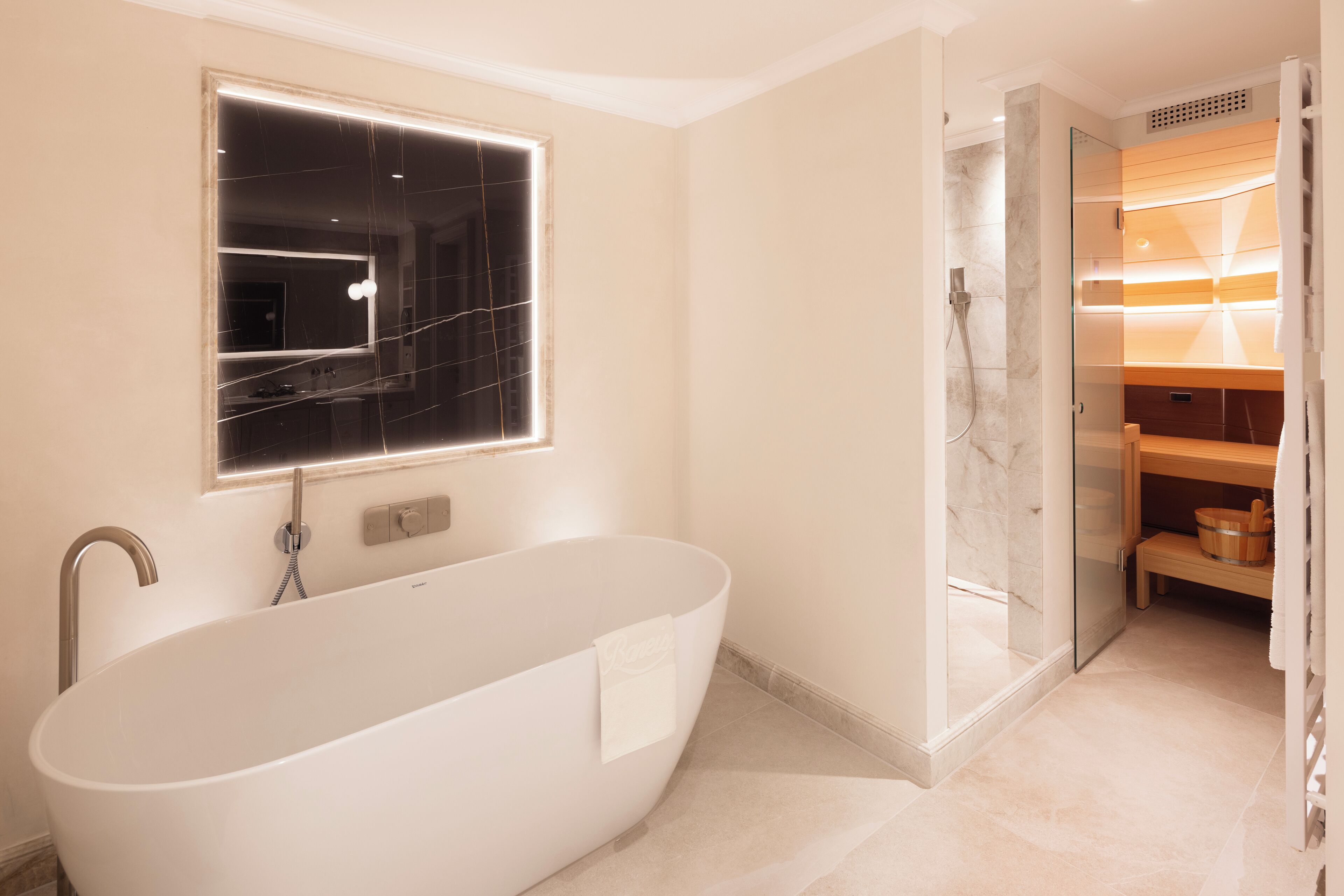 Ein modernes Badezimmer mit einer freistehenden Badewanne, einer gläsernen Dusche und einem Waschtisch mit Spiegel.