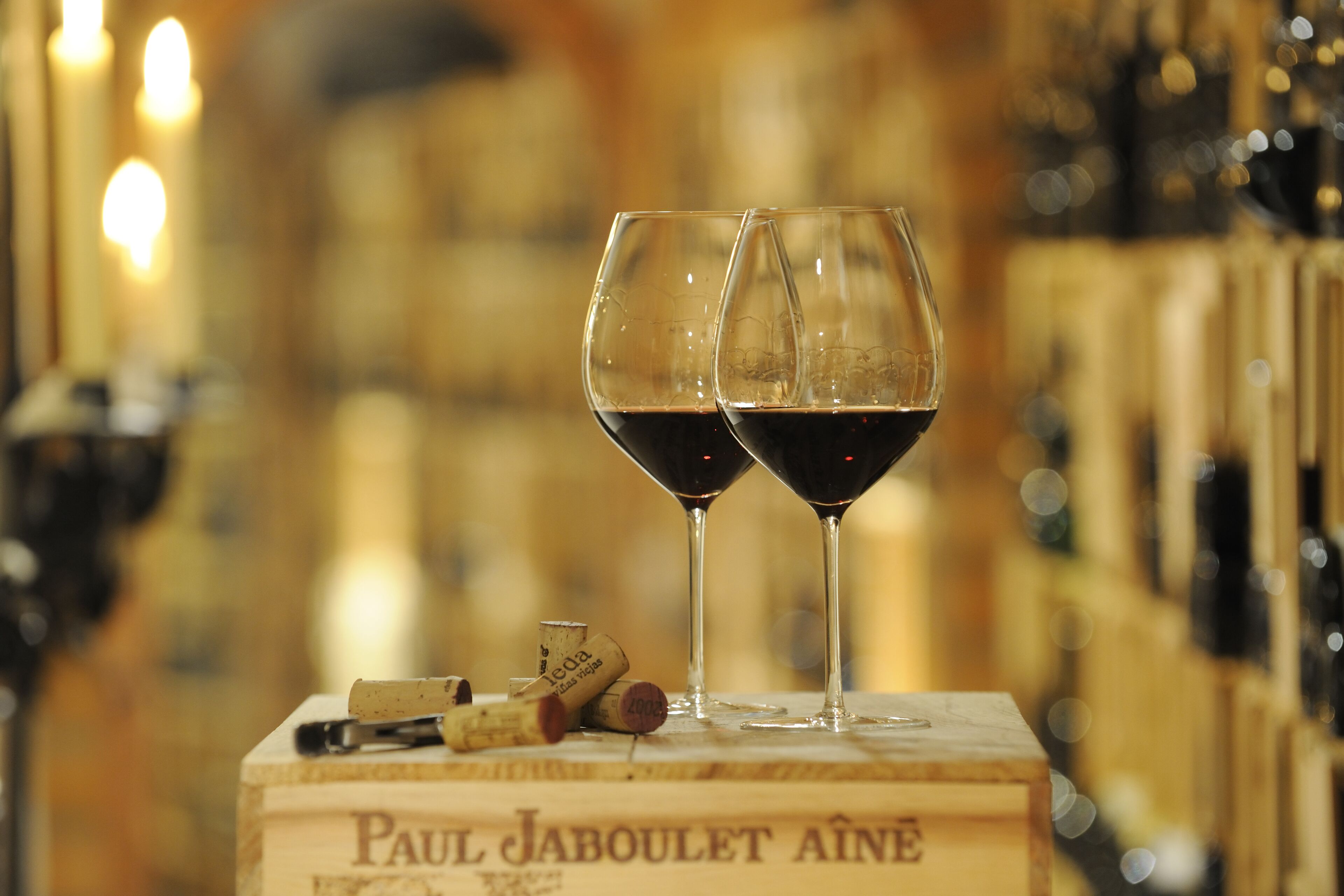 Two wine glasses filled with red wine on a wooden box labeled "Paul Jaboulet Ainé".