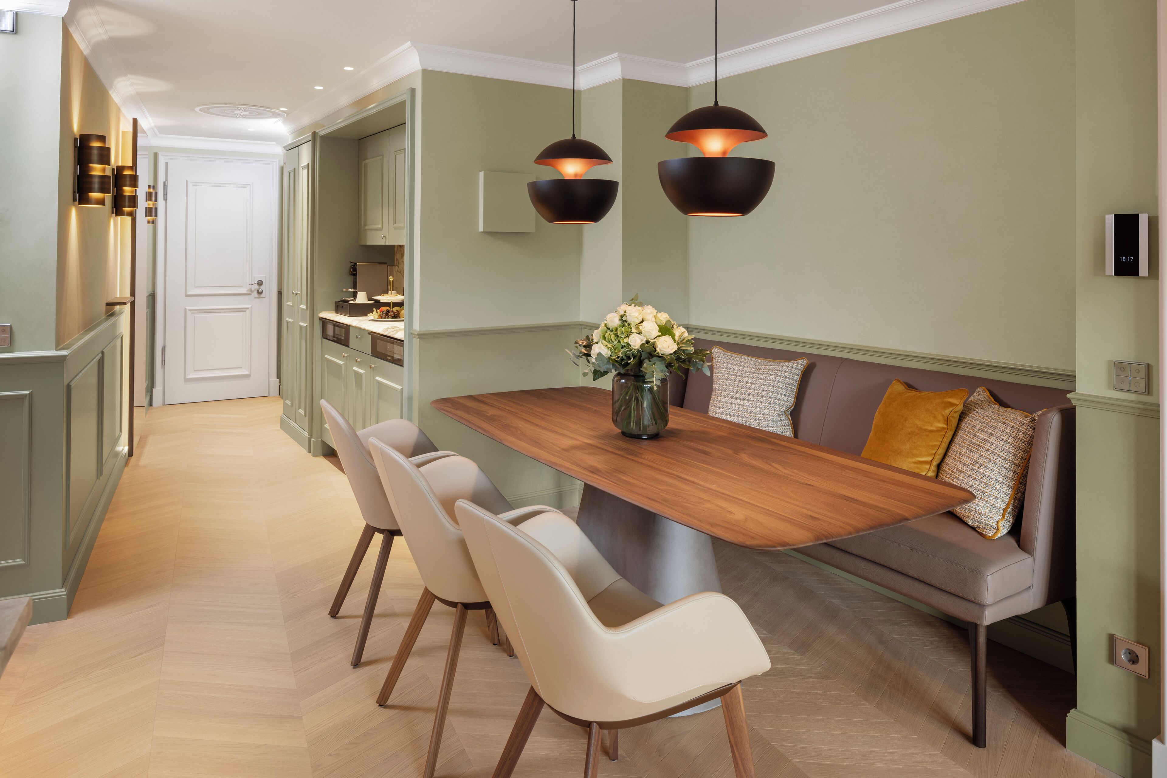 A modern kitchen with a wooden dining table, four chairs, and pendant lighting.