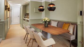 A modern kitchen with a wooden dining table, four chairs, and pendant lighting.