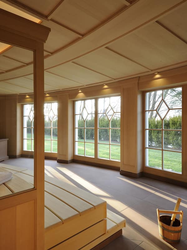 Relax in a serene space with a large bed, headboard, and mirror, surrounded by natural views and ample natural light.