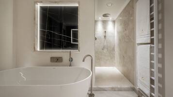 Un baño moderno con una bañera independiente, ducha a ras de suelo y un perchero con toallas dobladas con esmero.
