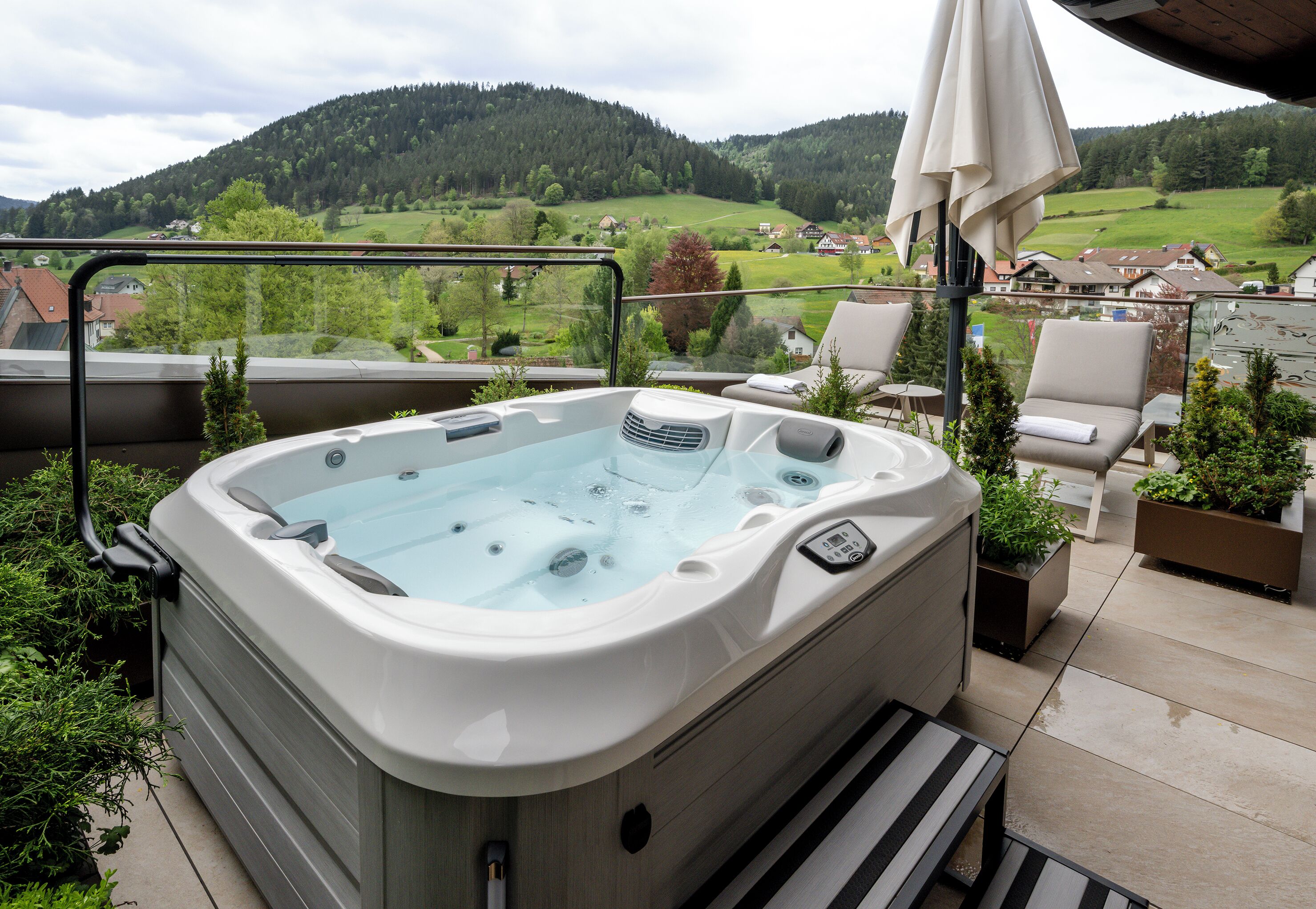 Ein Whirlpool mit Blick auf eine grüne Landschaft und Häuser im Hintergrund.