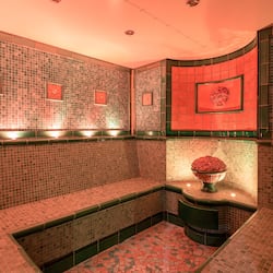 Bathroom features a mosaic tile design, a round mirror, and a decorative pedestal with flowers.
