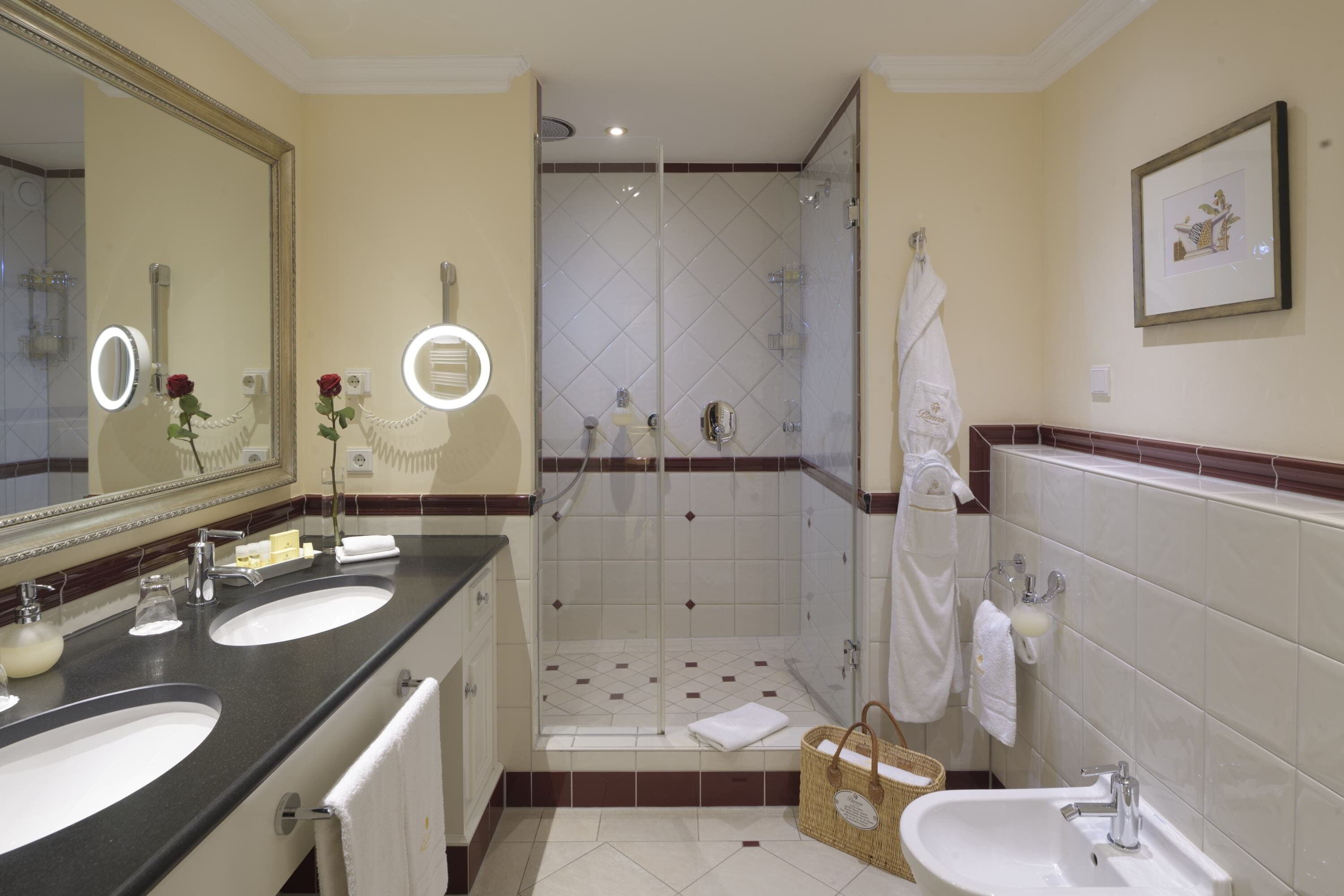A bathroom with two sinks, a shower, a large mirror, and a framed picture on the wall.