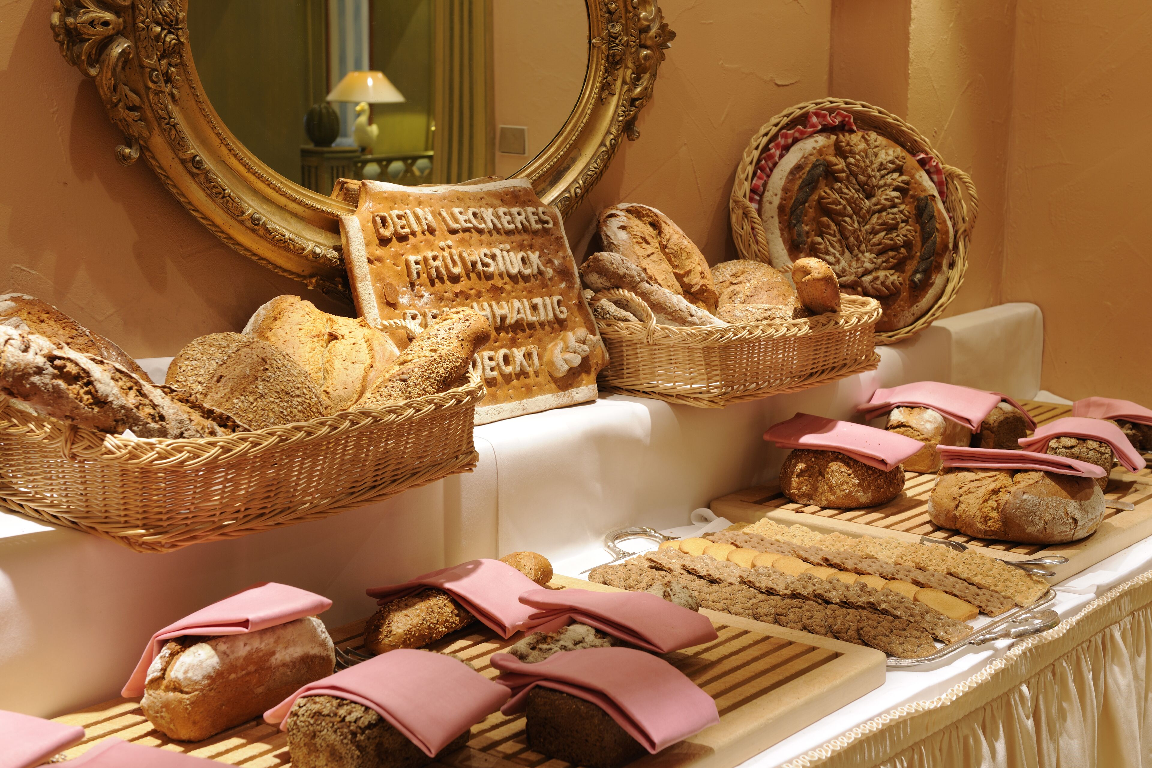 A buffet with various breads and pastries displayed on a table.