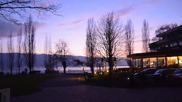 A lakeside view with a building featuring large windows and outdoor seating.