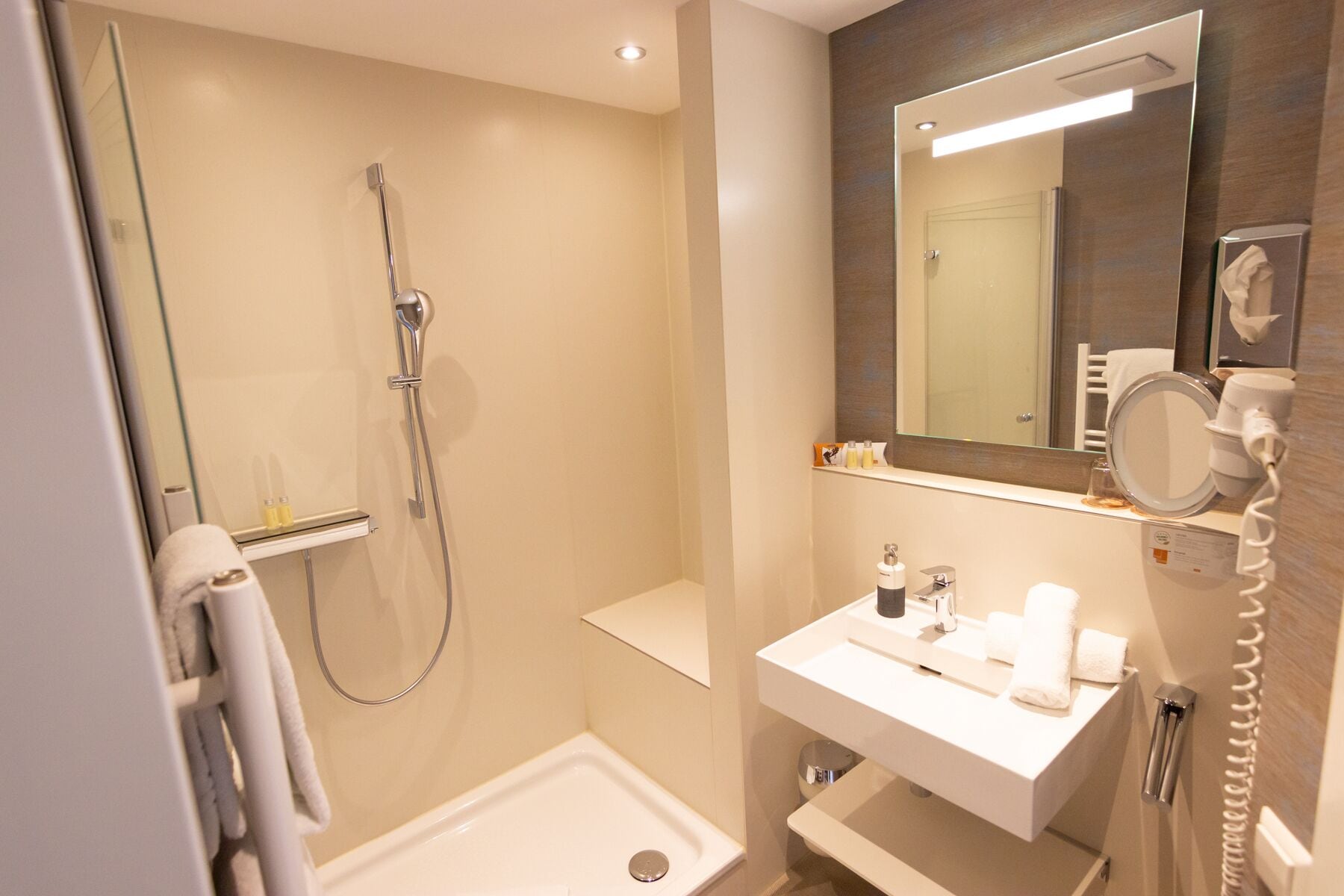 Ein modernes Badezimmer mit Dusche, Waschbecken und Spiegel.