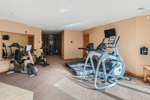 A gym with treadmills, stationary bikes, and a mirrored wall.