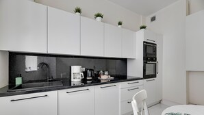 Uma cozinha moderna com armários brancos, bancada preta e forno embutido.