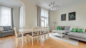 Uma sala de estar ampla com área de jantar, sofá cinza e duas obras de arte emolduradas na parede.