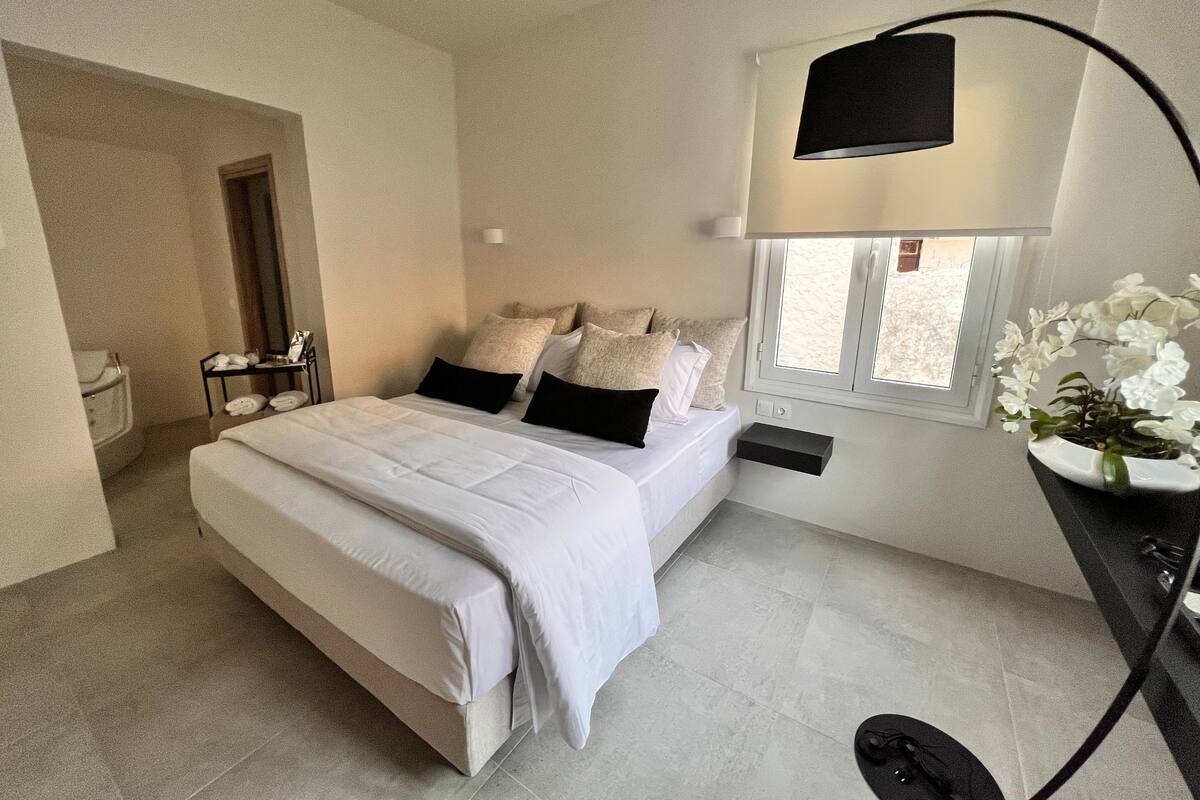 Une chambre moderne avec un grand lit, des tables de chevet, une commode, une fenêtre avec vue et une lampe de sol.