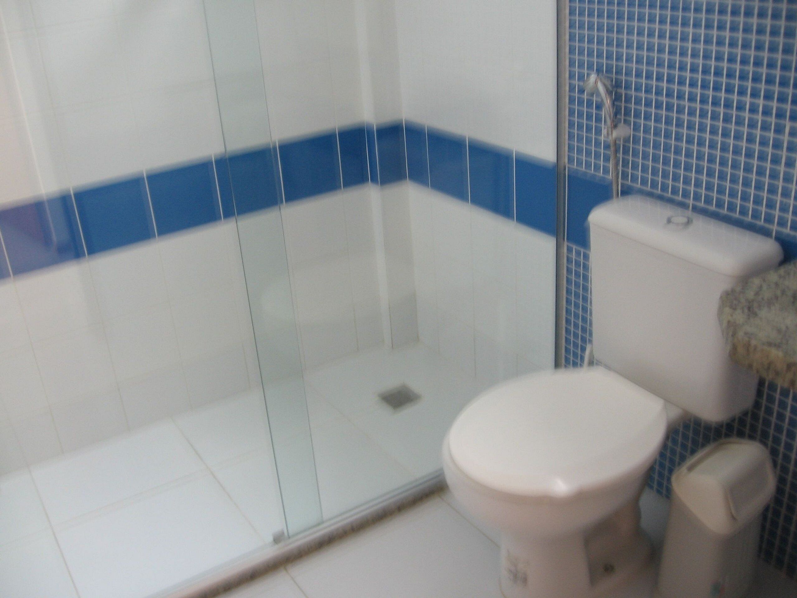 Et badeværelse med et glasbadeværelse, toilet og håndvask.