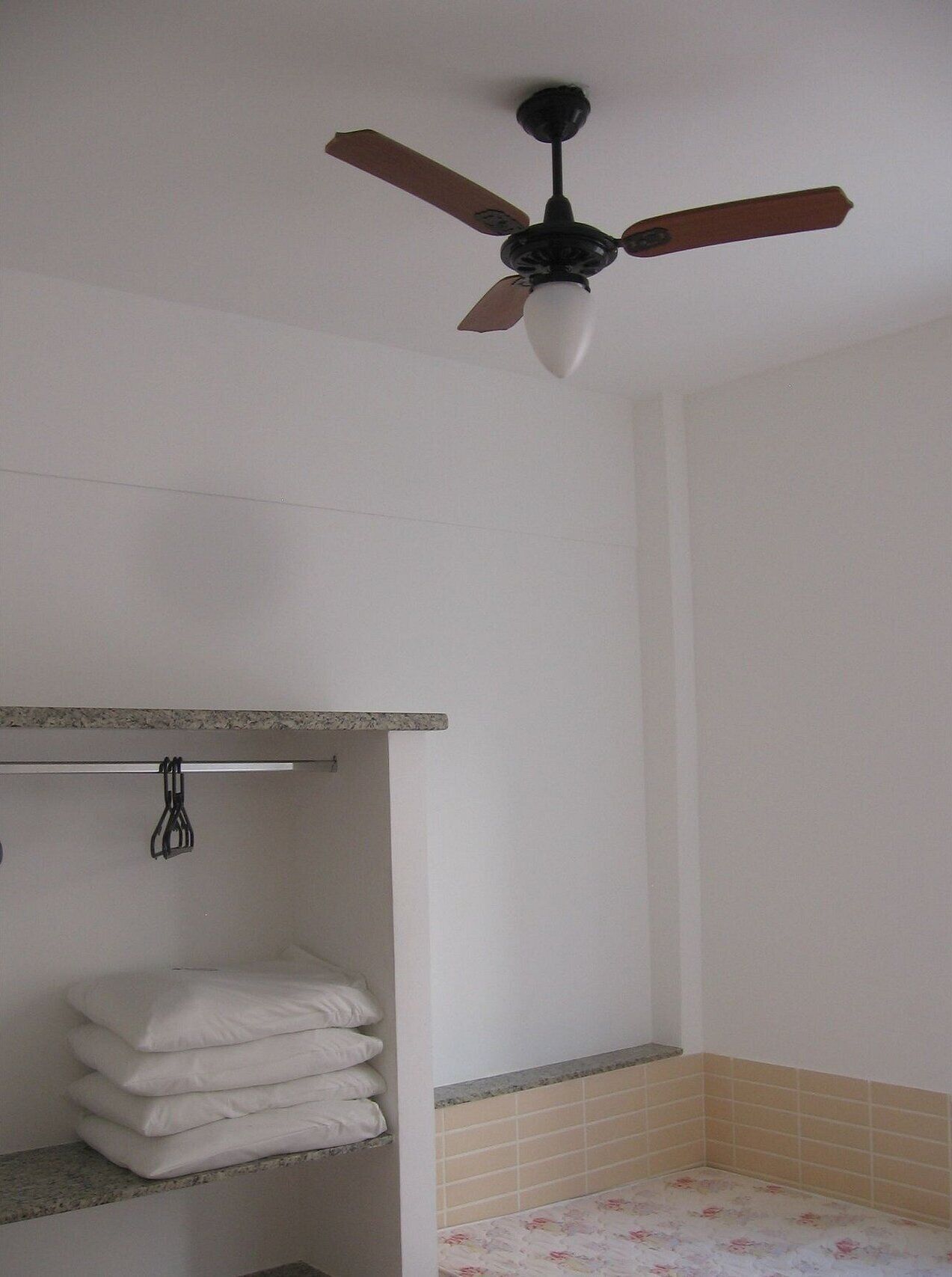 A bathroom with a ceiling fan, a towel rack, and a tiled shower area.