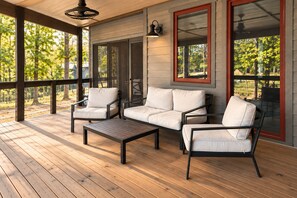 Un espace extérieur abrité, doté d’une terrasse en bois, d’un ensemble de canapés et d’une table.