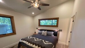 A bedroom with a bed, a ceiling fan, a window, and a door. - Pushin' Time Hideaway at The Retreat at Water's Edge (Tracy City)
