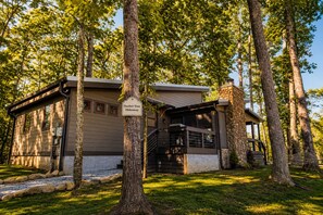Un chalet appelé « Feather Tree Hideaway », doté d’une cheminée en pierre, d’un porche couvert et d  ’un escalier menant à l’entrée.