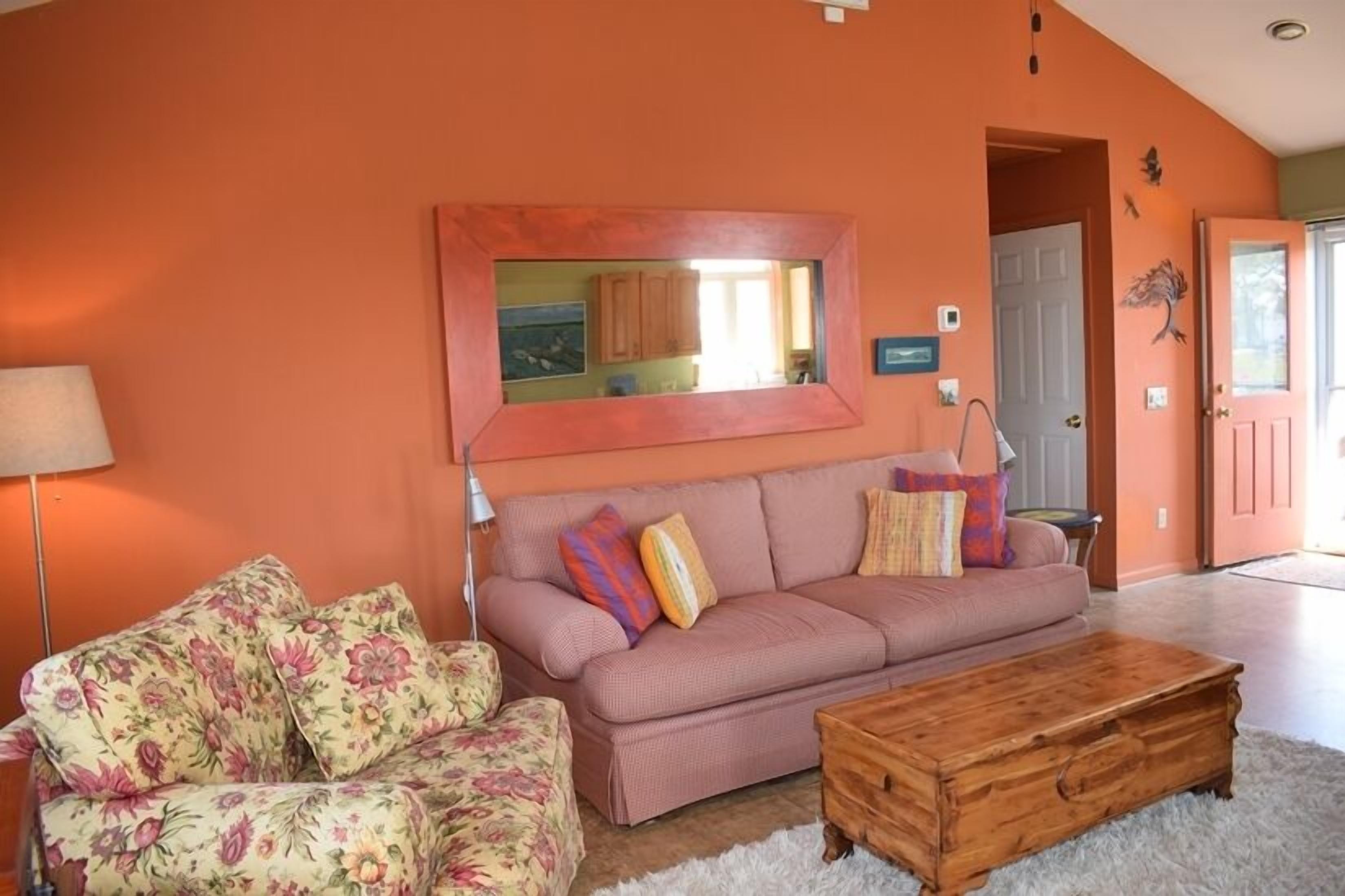 A living room with a sofa, a coffee table, and a large mirror on the wall.