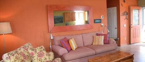 A living room with a sofa, a coffee table, and a large mirror on the wall.