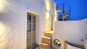 A modern, white-walled building with a spiral staircase leading to a balcony.