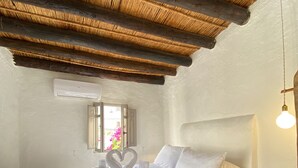 A spacious bedroom with a large bed, a wooden ceiling, and a small bedside table with a lamp.