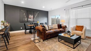 Ein modernes Wohnzimmer mit einer Ledersofa, einem Glastisch und einem Essbereich mit Holztisch und Stühlen.