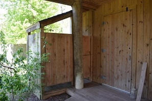 Una estructura de madera con un porche, una puerta de madera y una ventana.