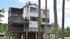 Ein mehrstöckiges Haus mit einem Balkon im ersten Stock und einer überdachten Veranda.