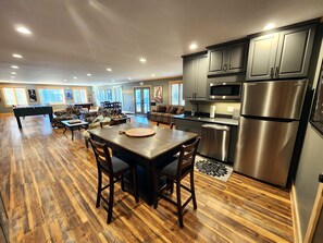 A spacious living area with a pool table, a dining table with chairs, and a kitchen with stainless steel appliances. - Treehouse- Fire Pit, Basketball Court, Bikes, Kayaks & Casita w/ Game Room (Chincoteague)