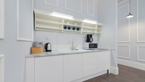 Eine moderne Küche mit weißen Schränken, einer eingebauten Mikrowelle und einer Kaffeemaschine.