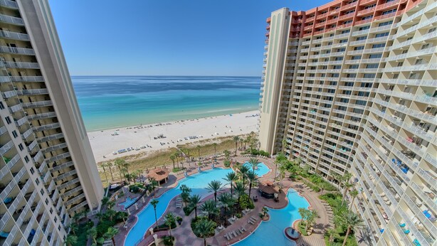 A high-rise hotel with a pool area, beach view, and multiple balconies.