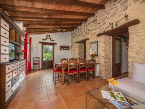A dining area with wooden chairs and a table, a stone wall, and a wooden ceiling. - Villa Can Cosme · Your villa with private pool in Alcúdia. (Alcúdia)