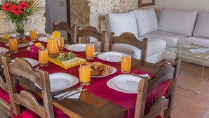 A dining table set with plates, cutlery, glasses of orange juice, and a fruit tray. - Villa Can Cosme (Alcúdia)