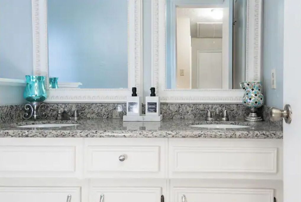 A bathroom with two sinks, a large mirror, and a decorative vase.