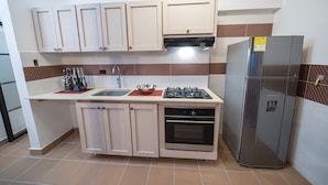 A compact kitchen with light wooden cabinets, a stainless steel refrigerator, a gas stove, and a built-in oven. - Cozy 1BR APT in the Heart of Medellin (Medellín)