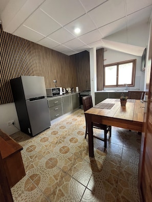 A kitchen with a refrigerator, microwave, stove, and dining table with chairs.