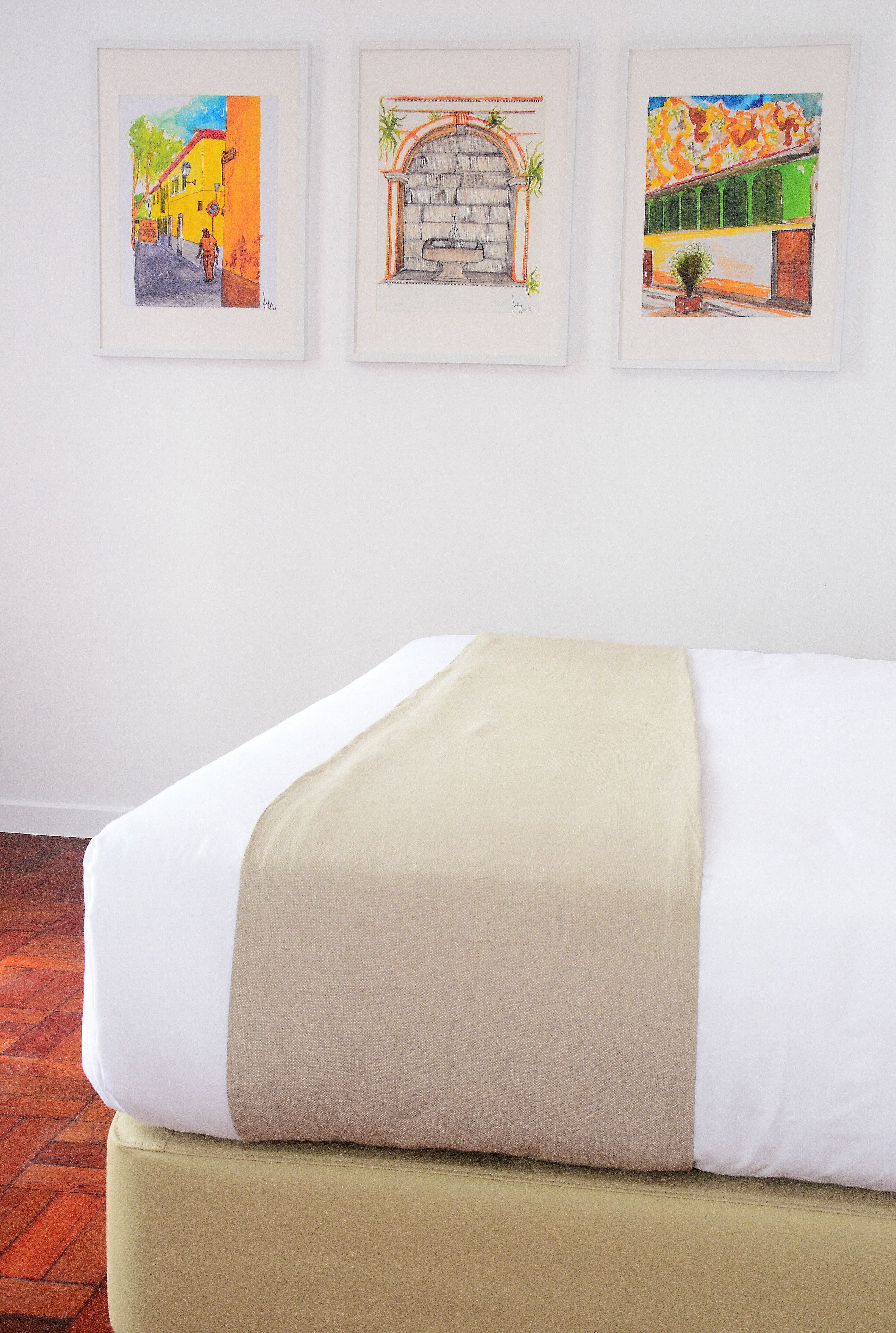 Een bed met een beige deken, een wit kussen en een groen hoofdeinde.