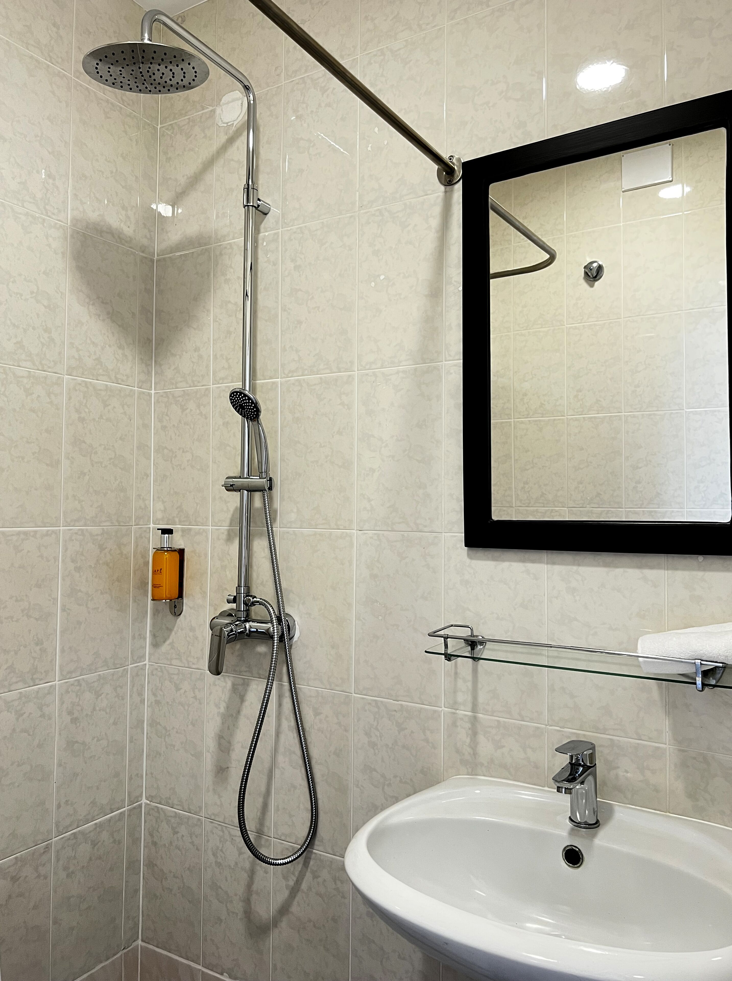A bathroom with a shower, sink, and mirror.