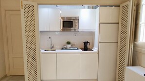 Een kleine keuken met een magnetron, spoelbak en koffiezetapparaat.