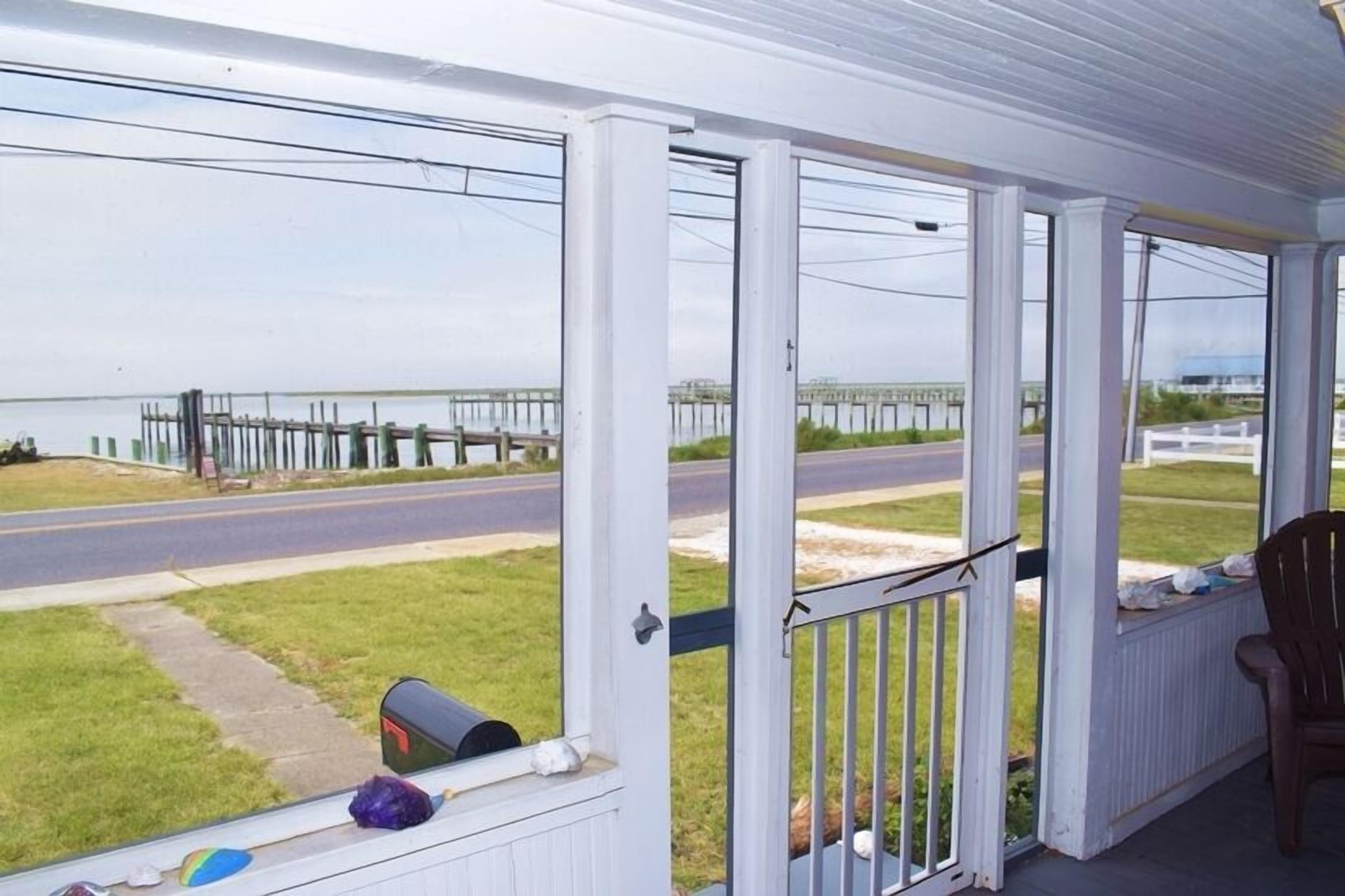 A covered porch with a view of a road and a bridge.