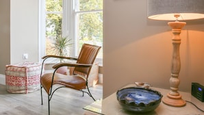 Une pièce comprenant une chaise en bois, une table en verre, un bol, une lampe et une fenêtre donnant sur des arbres.
