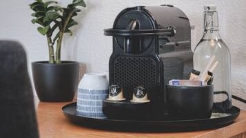 A coffee machine on a tray with a plant, a cup, and a bottle.