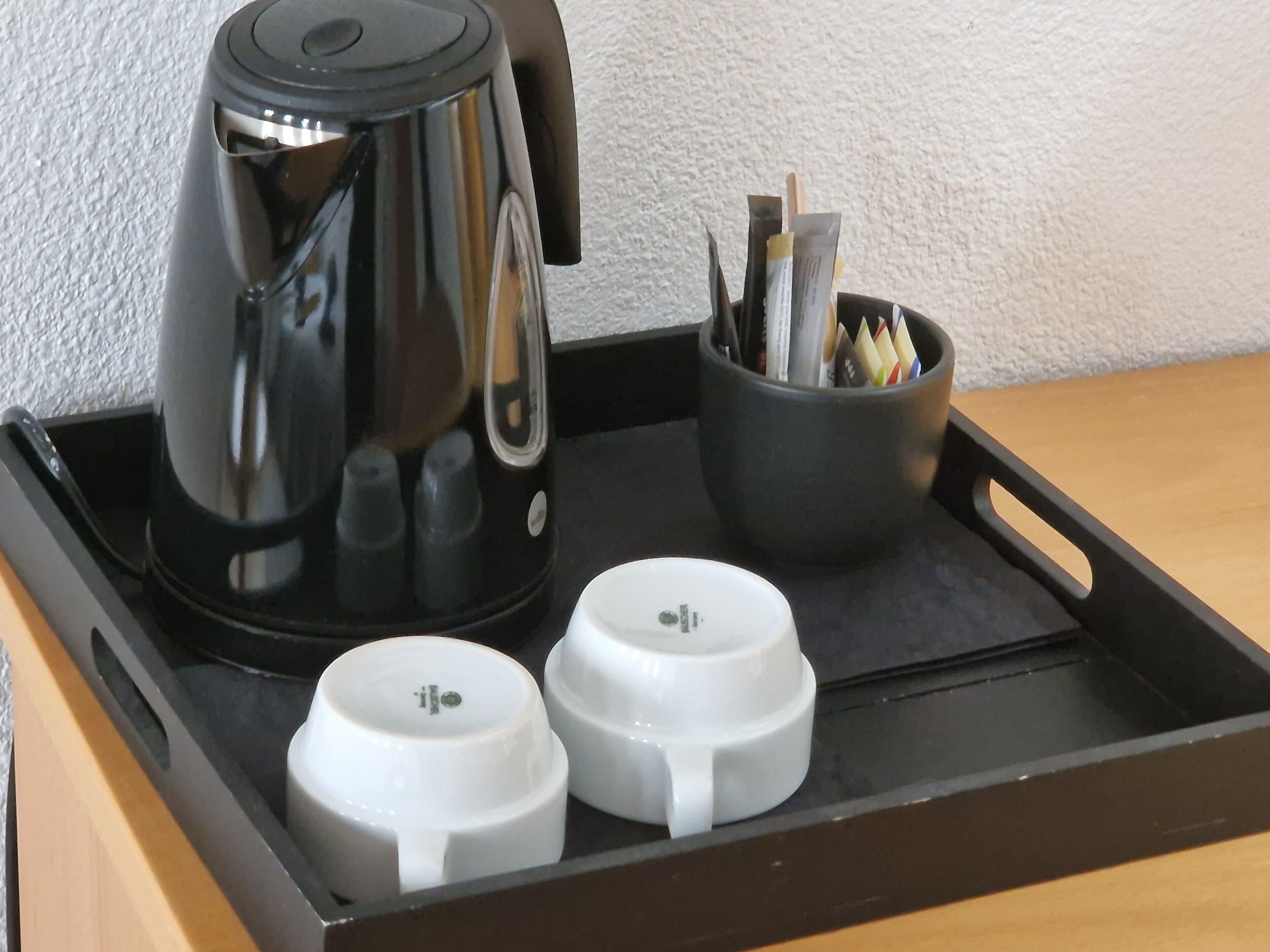 Ein schwarzes Tablett mit einer Kaffeemaschine, zwei weißen Tassen und einer Aufbewahrungsbox f ür Stifte und Marker.