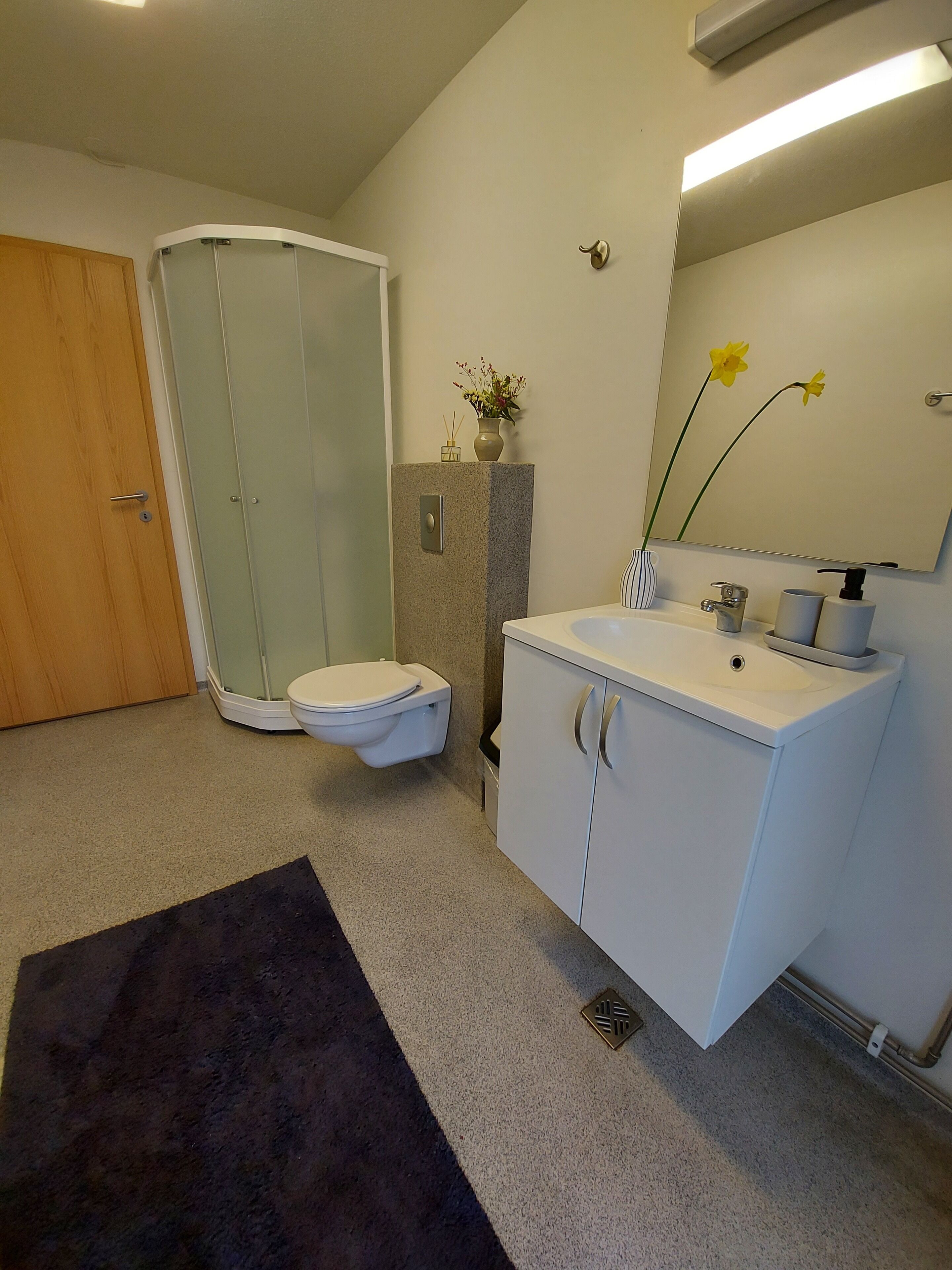 A bathroom with a toilet, shower, and sink.