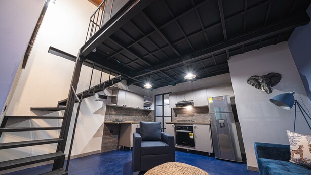 A modern interior with a staircase, a sofa, a chair, and a kitchen area. - BEST Location 1BedR - Heart of Medellin (Medellín)