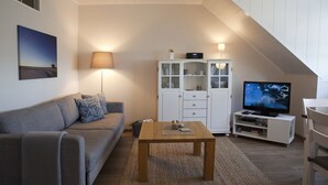 Ein Wohnzimmer mit einer Couch, einem Couchtisch, einem Fernseher und einem Schrank.